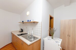 A compact kitchen with a built-in stove, a sink, and a wooden cabinet with drawers. - Rooms Nada (Seline)