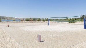 An outdoor volleyball court with a net, surrounded by a gravel surface and a clear sky. - Rooms Nada (Seline)