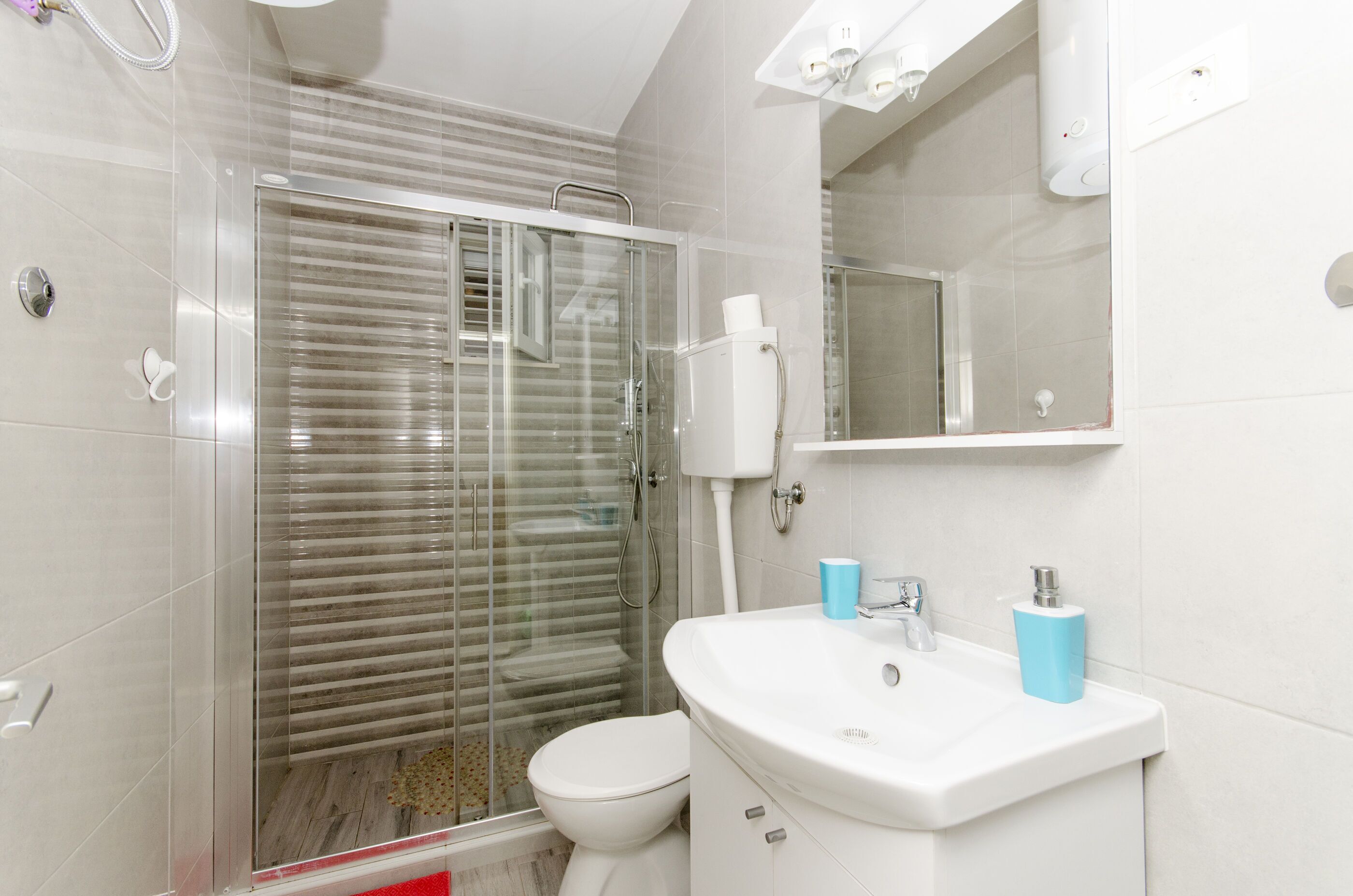 Une salle de bain moderne avec une douche à parois de verre, des toilettes blanches et un lavabo avec un miroir au-dessus.