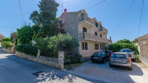 A two-story building with a stone facade, a balcony on the upper floor, and a parked car in front. - Apartments Kata (Supetar)