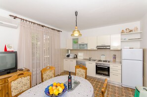 A compact kitchen with a dining table, chairs, a TV, and a refrigerator.