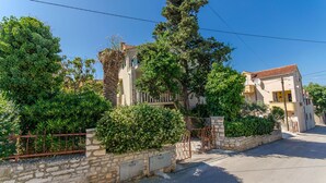 A residential street with houses, a stone wall, and a gate. - Apartments Kata (Supetar)