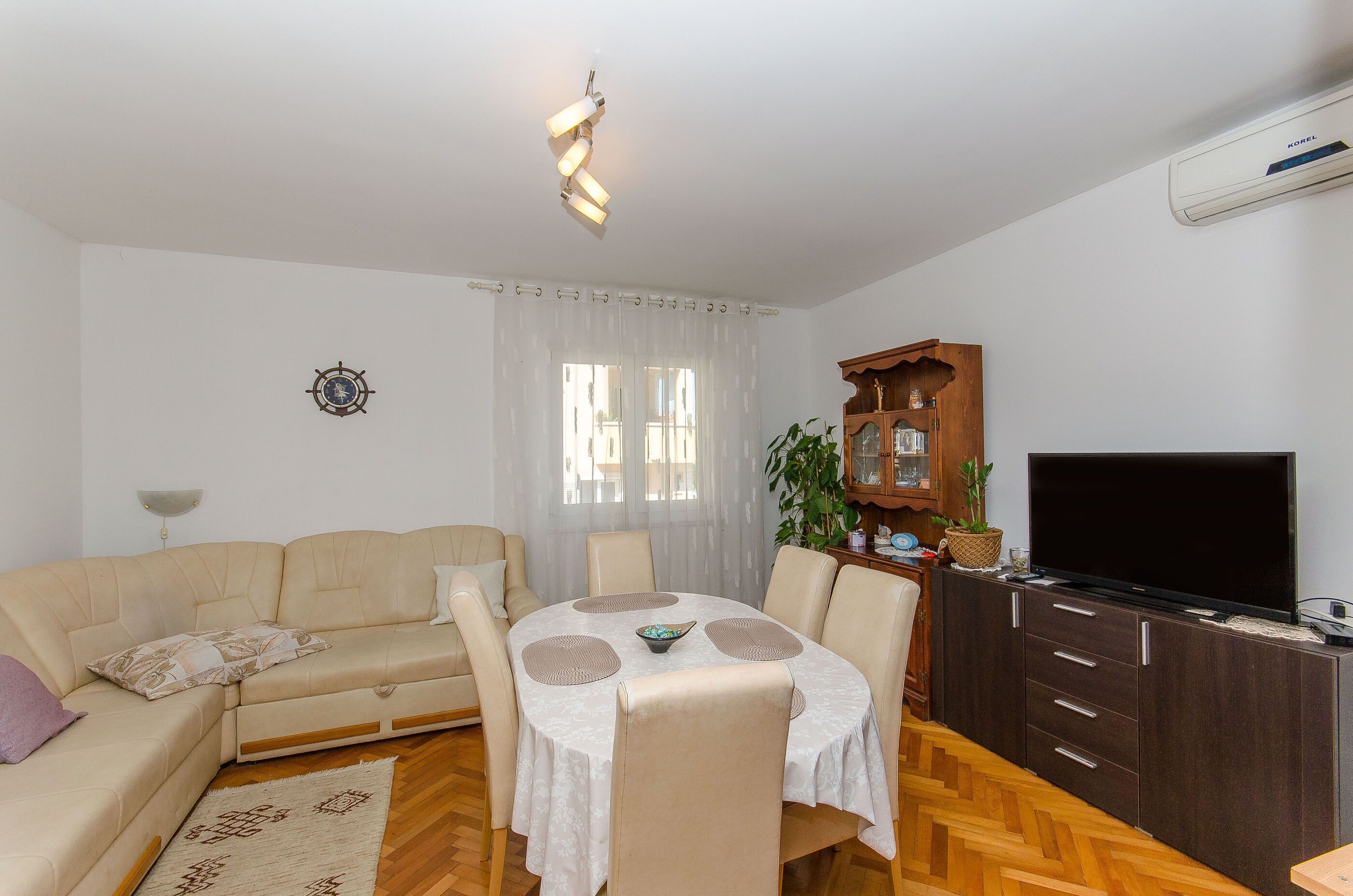 A living room with a sofa, dining table, chairs, a TV, and a wooden cabinet.
