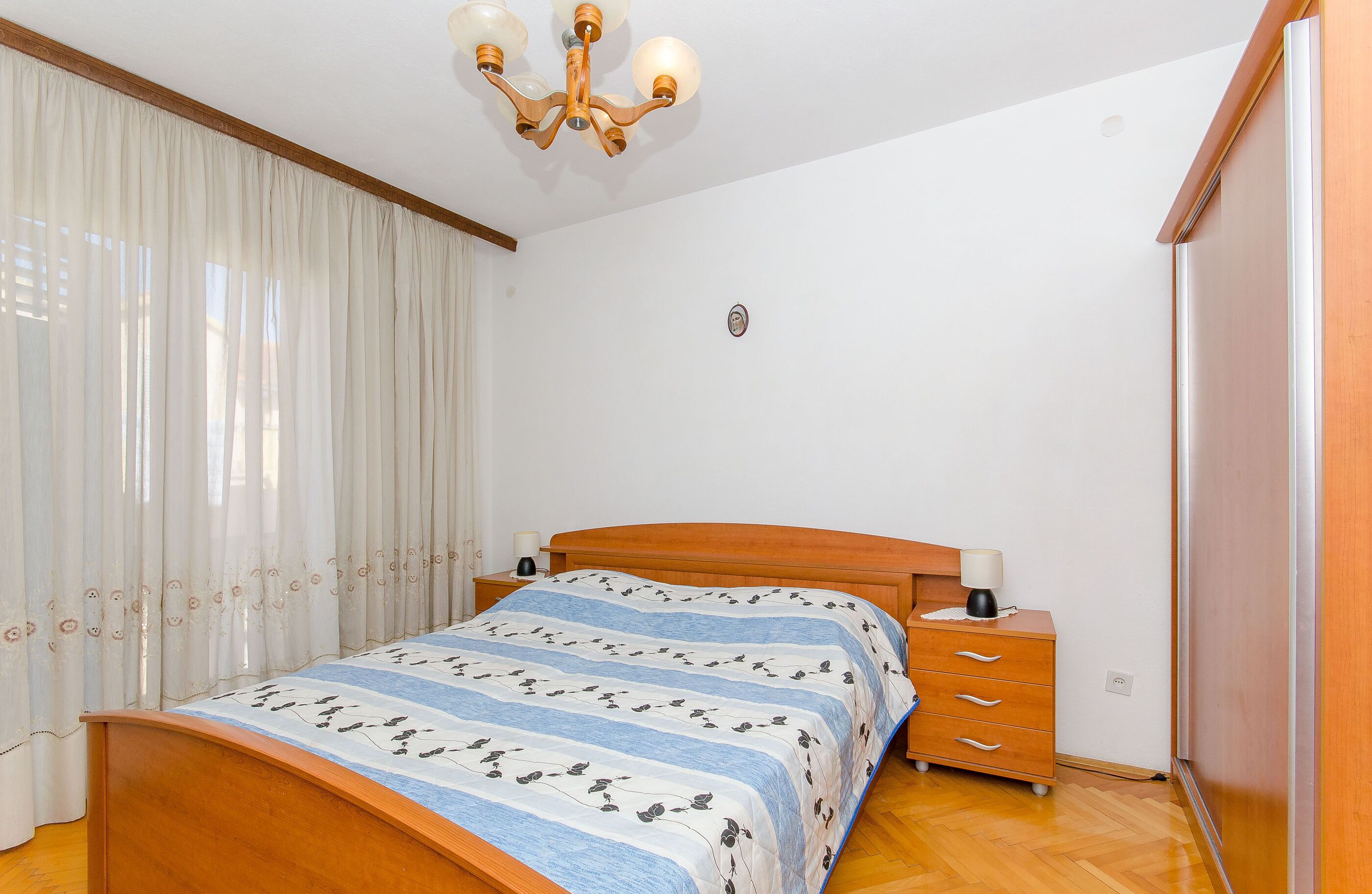 A bedroom with a wooden bed, a nightstand, a lamp, and a wardrobe.