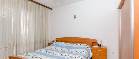 A bedroom with a wooden bed, a nightstand, a lamp, and a wardrobe.
