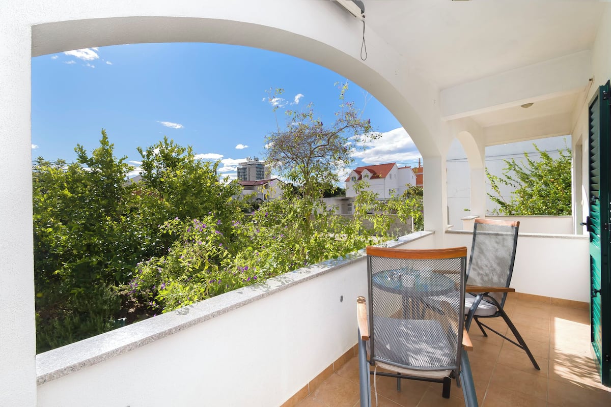 A balcony with a view of greenery and buildings.