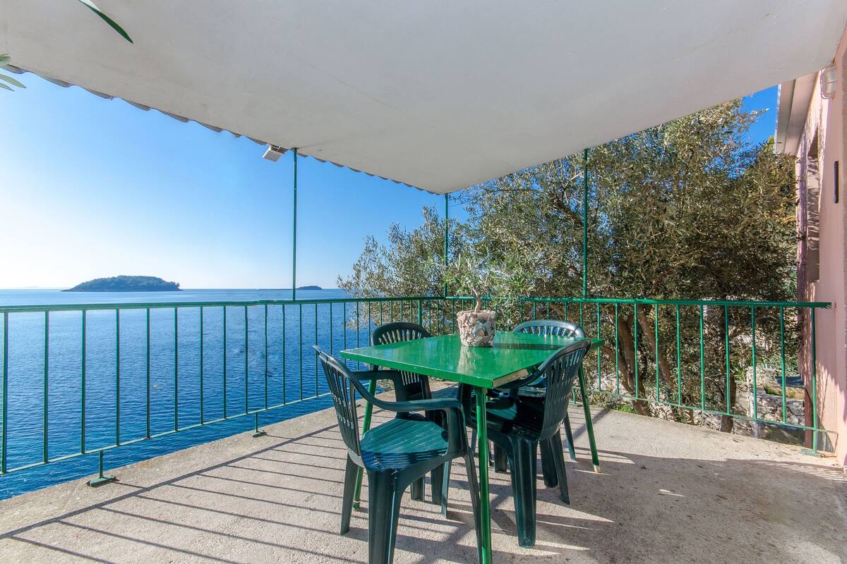 A balcony with a table and chairs overlooking a body of water.