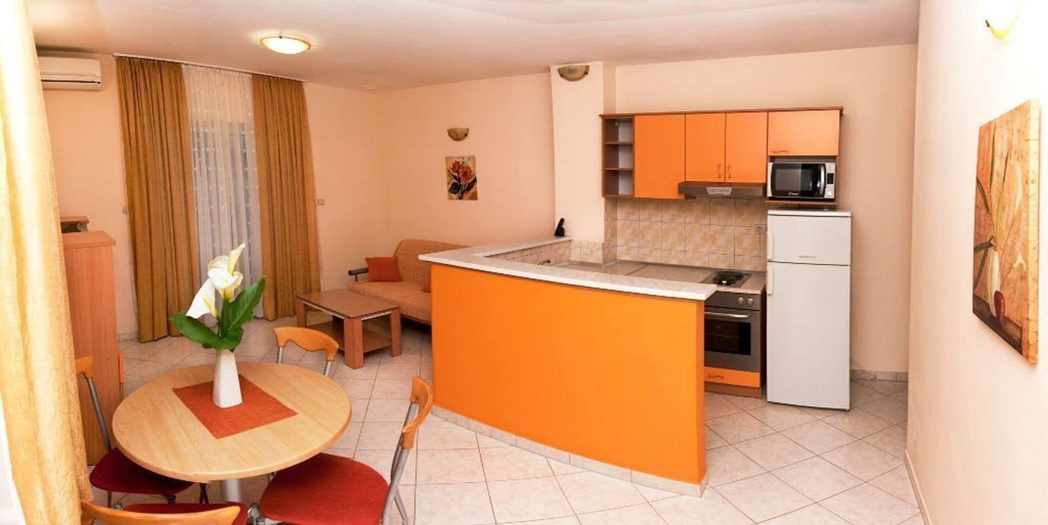 A compact kitchen with a small island, a dining area with a table and chairs, and a living space with a sofa.