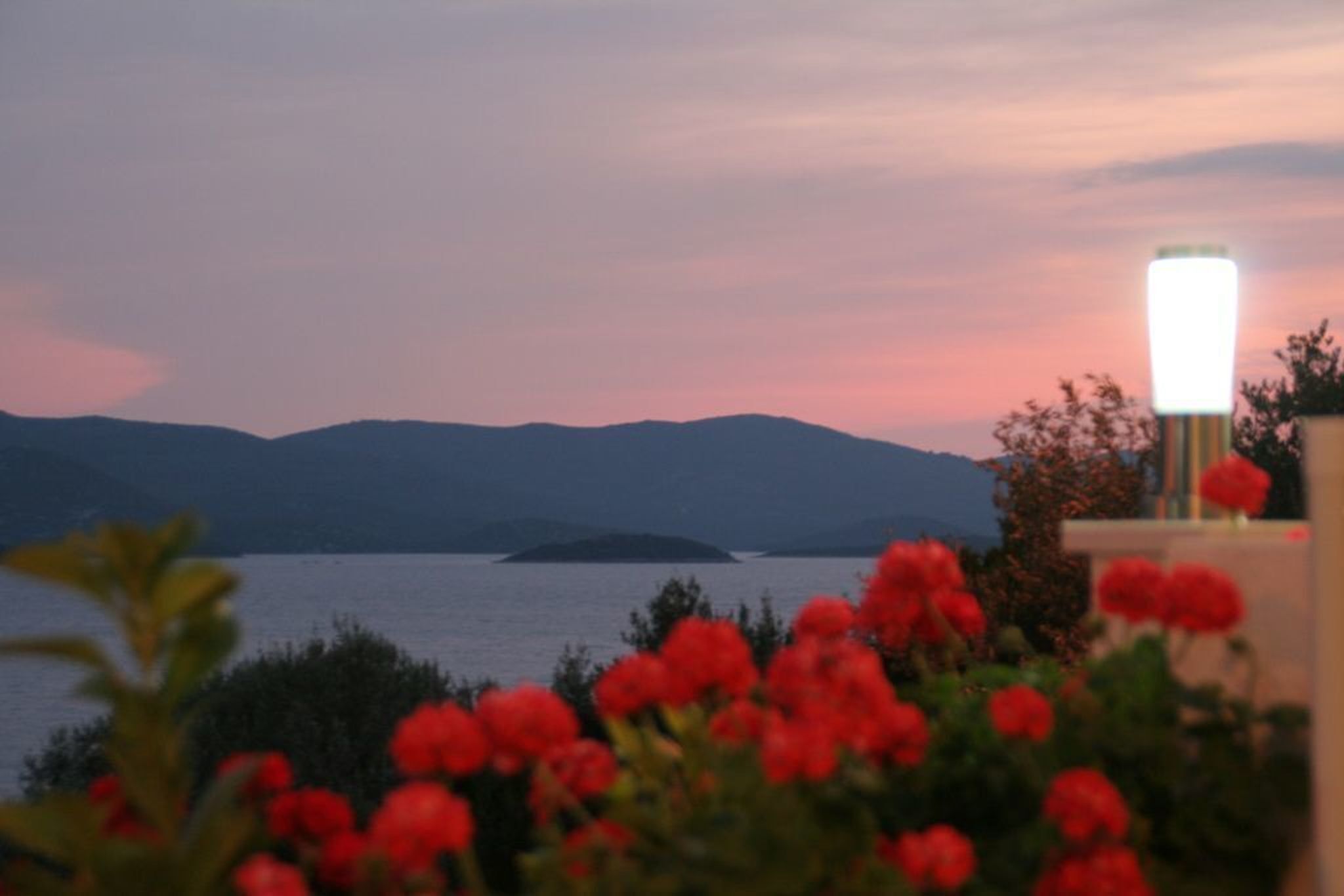 A view of a body of water with mountains in the background and a street lamp in the foreground.