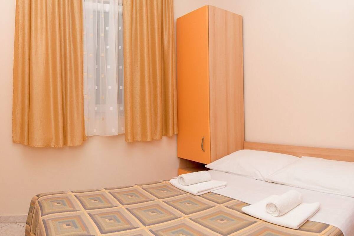 A hotel room with a bed, a wardrobe, and a window with curtains.