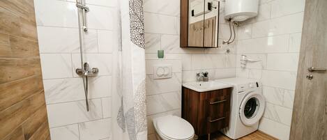 A modern bathroom with a shower, toilet, sink, and washing machine.