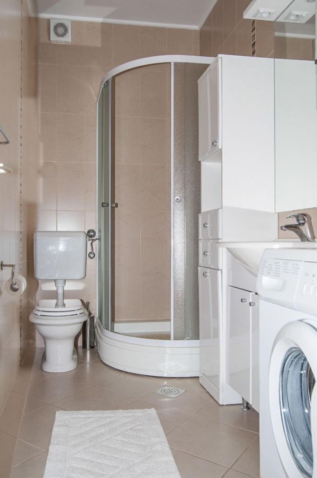 A bathroom with a toilet, a shower enclosure, and a washing machine.