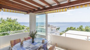 Un balcon avec une table et des chaises, offrant une vue sur la côte.