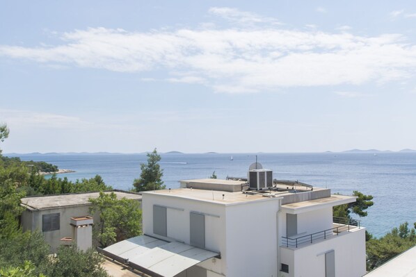 A modern building with a flat roof, large windows, and a view of the sea. - Apartment Branka (Murter)