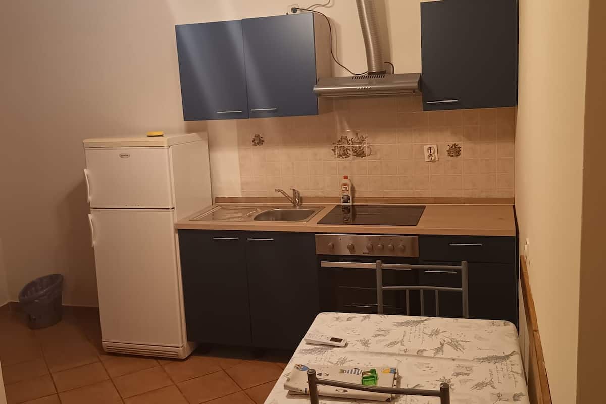 Una cocina compacta con refrigerador, estufa, pileta y ventilador de techo.