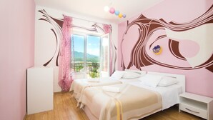 A bedroom with two beds, a window with a view, and a decorative wall design. - Apartments Jelka (Jelsa)
