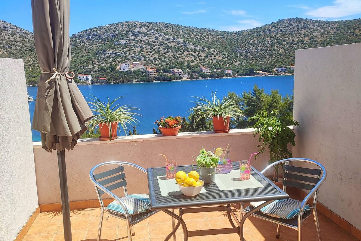 Una terrazza con tavolo, sedie, ombrellone e piante in vaso.