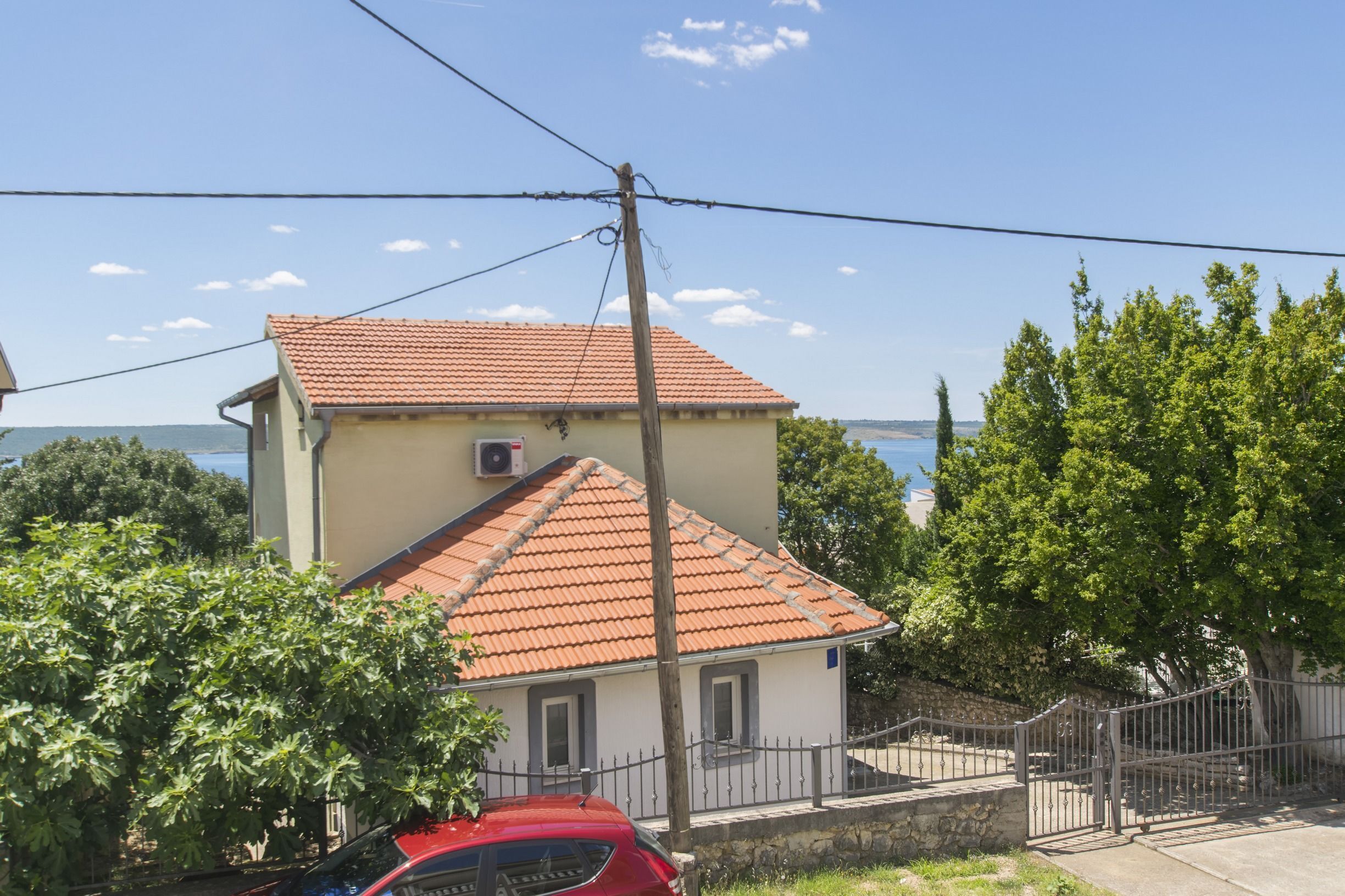 Ein zweistöckiges Haus mit rotem Ziegeldach, einem kleinen Balkon und Blick aufs Meer.