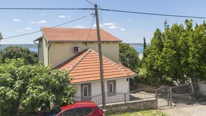 A two-story house with a red-tiled roof, a small balcony, and a view of the sea. - House Iva (Maslenica)