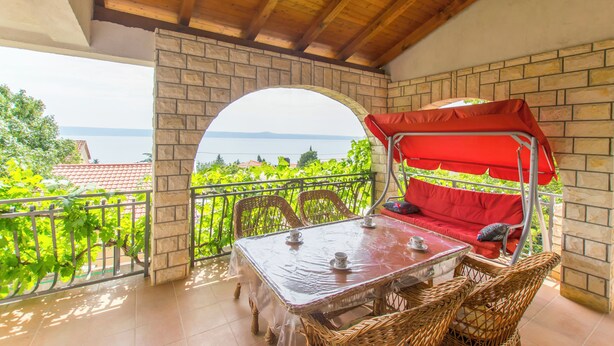 A balcony with a table, chairs, and a red canopy bed. - House Iva (Maslenica)