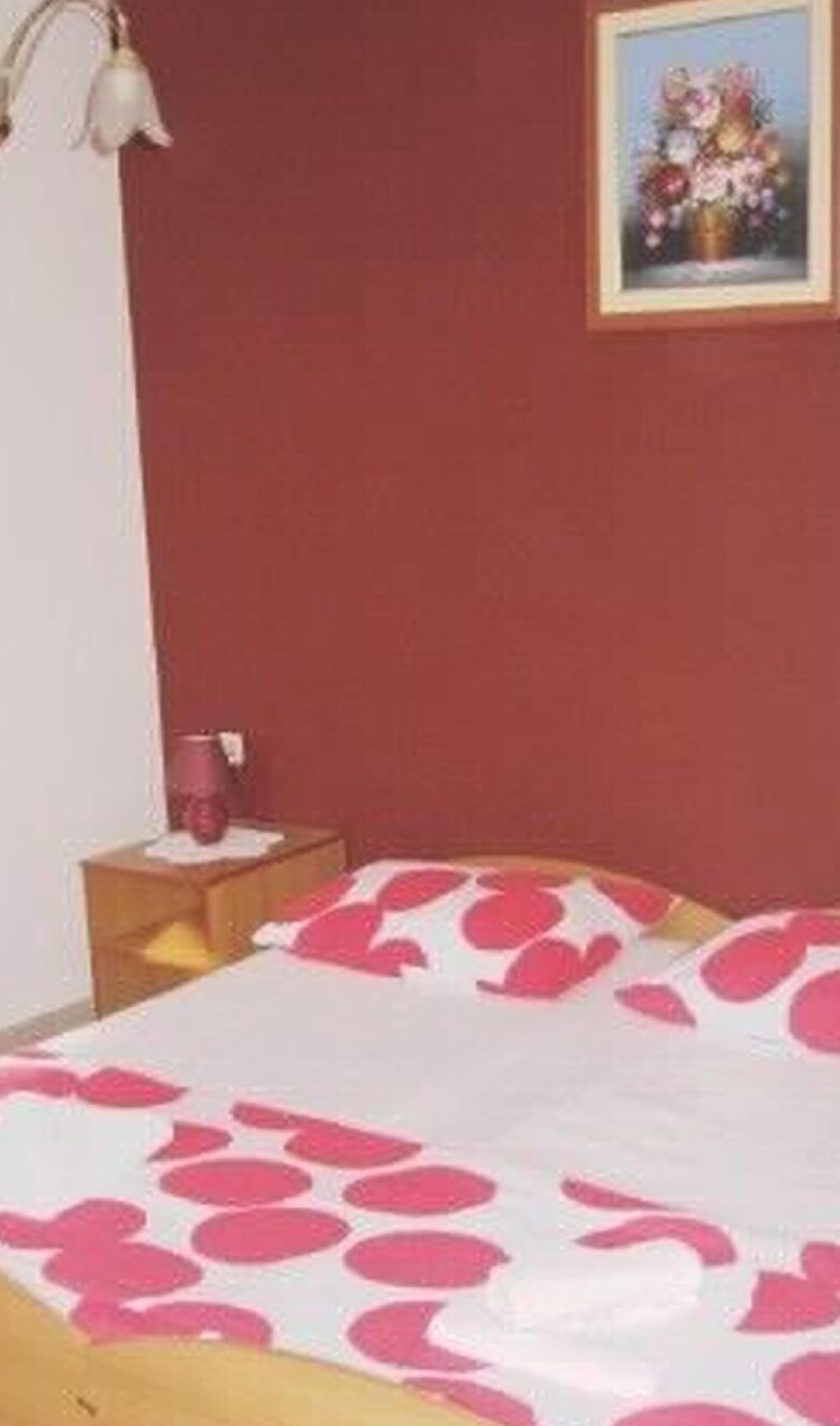 Een kamer met een bed, een nachtkastje, een lamp en een lijst met een afbeelding aan de muur.