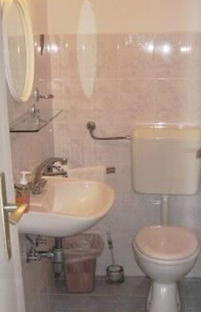 A bathroom with a sink, toilet, and mirror.