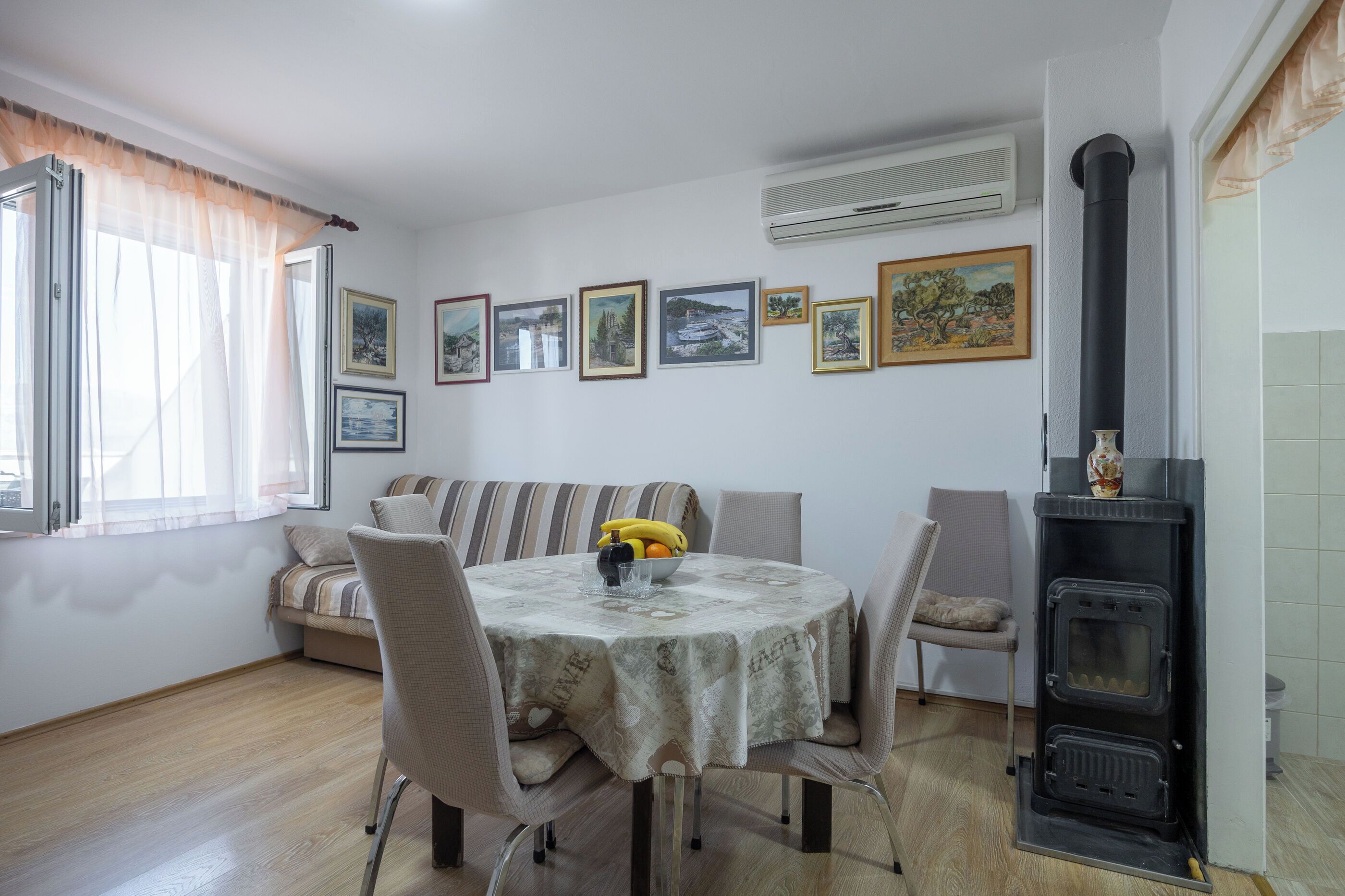 A dining area with a round table, chairs, a sofa, and a black wood-burning stove.