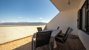 A terrace with a table and chairs, a view of mountains, and a tiled floor. - Apartment Toma (Supetar)