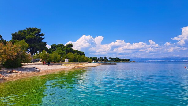 A clear coastal area with a pebble beach, trees, and a calm sea. - Apartment Toma (Supetar)