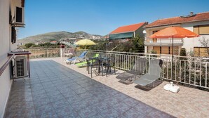 Una terrazza con pavimento piastrellato, arredi da esterno e vista su un paesaggio collinare.