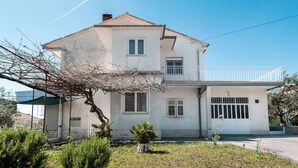 Una casa a due piani con un balcone, un garage e un giardino.