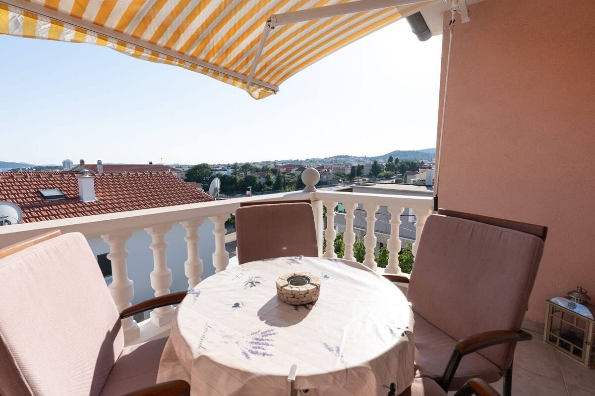 Ein Balkon mit Tisch, Stühlen und Blick auf die Stadt.