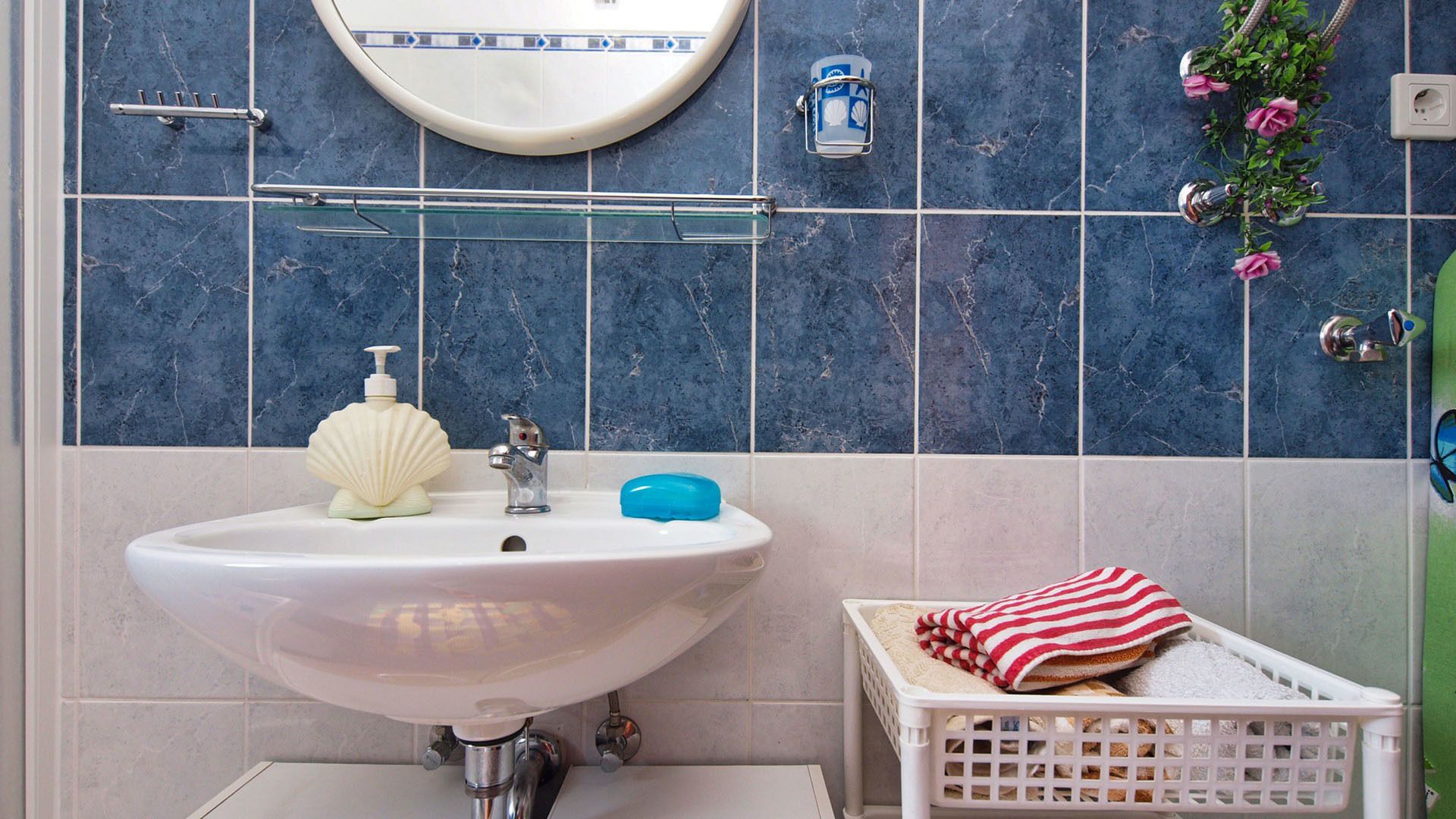 Een badkamer met een witte wastafel, een spiegel en een blauw betegelde wand.