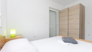 Una habitación de hotel con cama, mesita de noche con lámpara, armario y puerta.