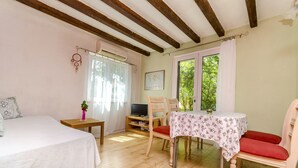 Une pièce confortable avec un lit, une petite table sur laquelle se trouve un téléviseur, une chaise et une fenêtre avec des rideaux.