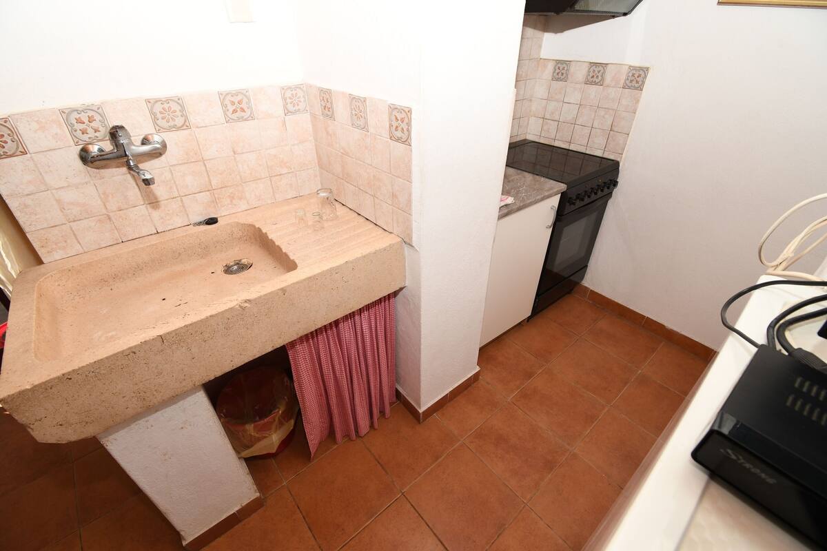 A small kitchen with a sink, a stove, and a countertop.