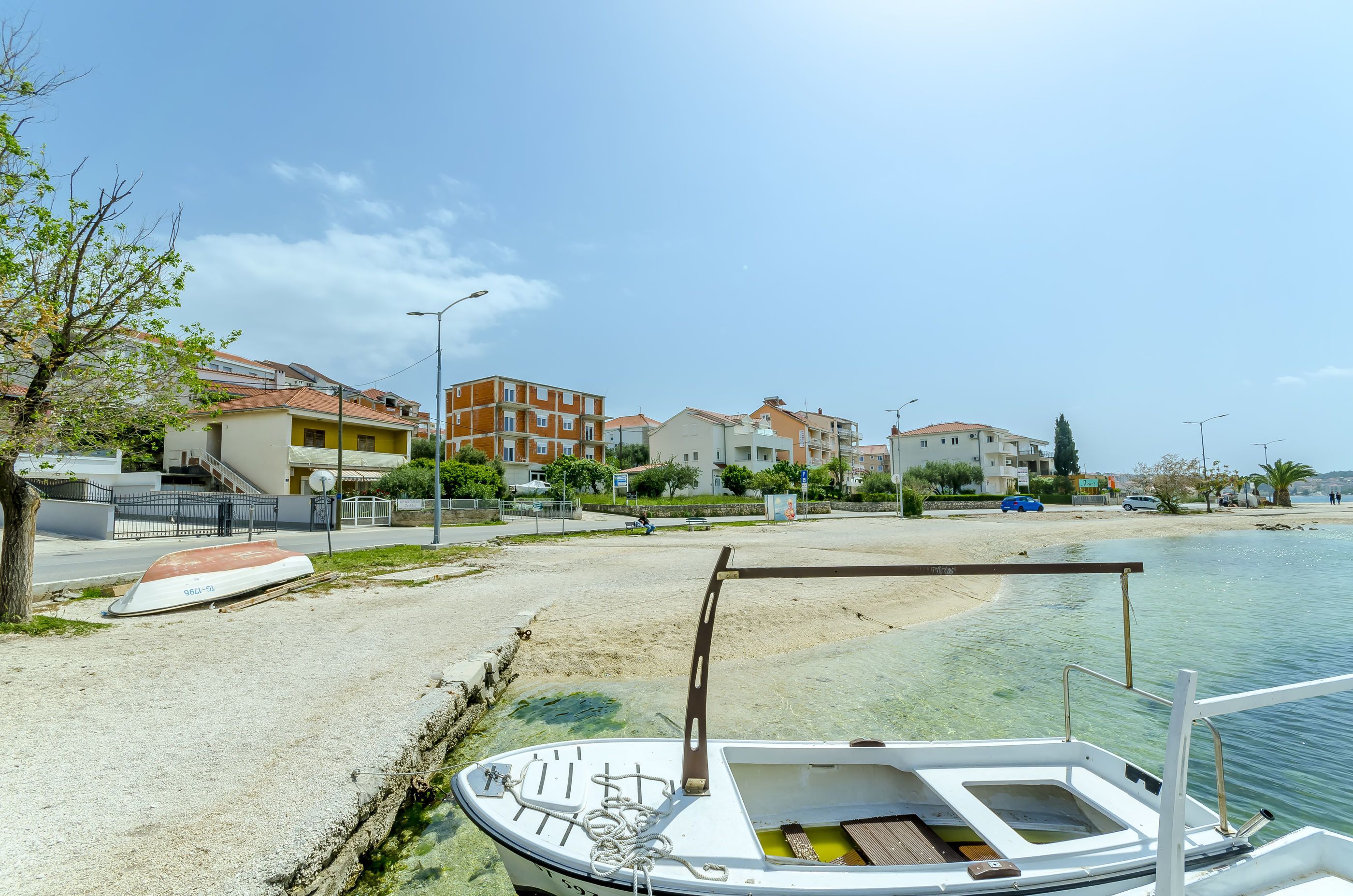 A boat docked at a sandy beach with buildings in the background.