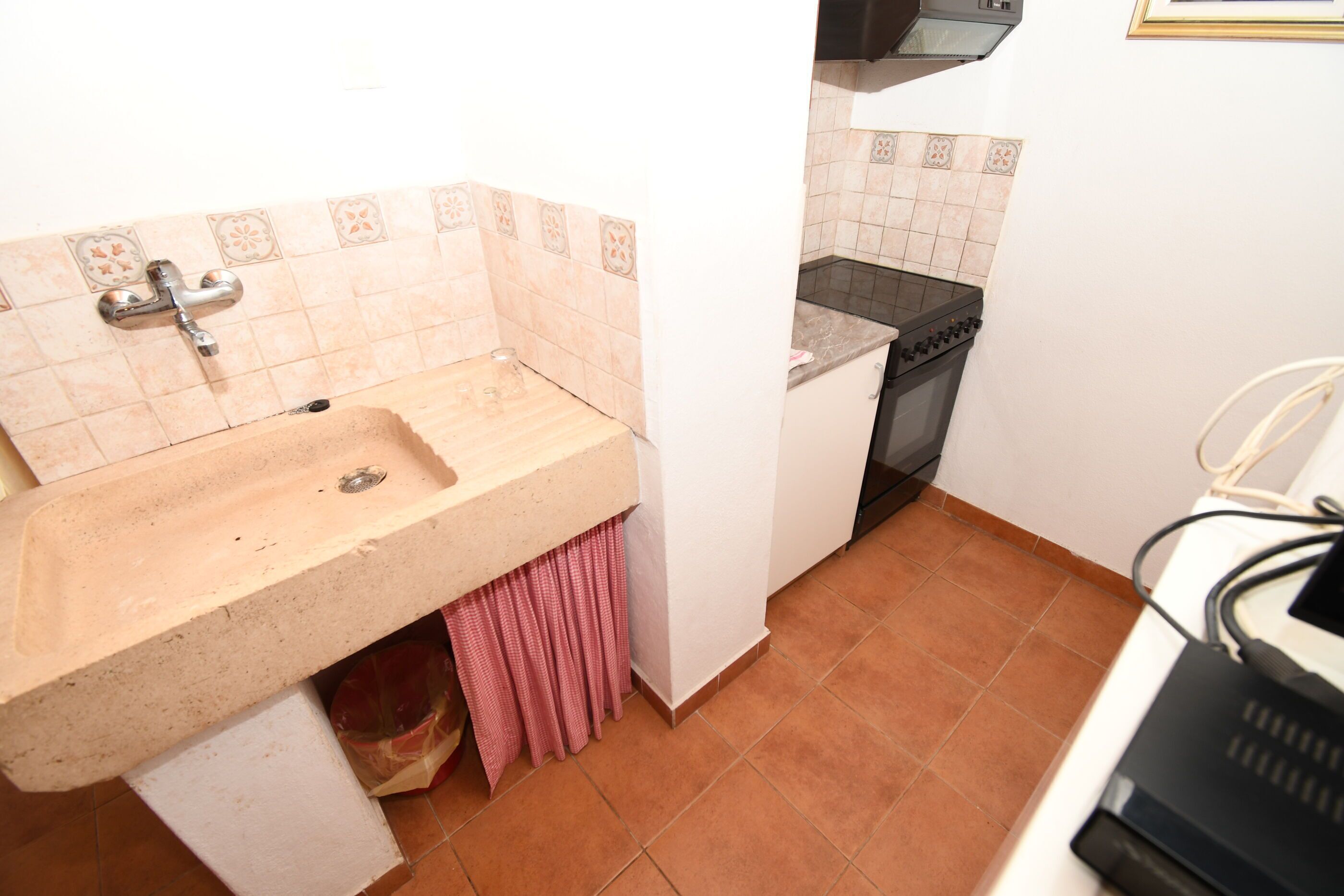 A kitchen with a sink, stove, and tiled backsplash.