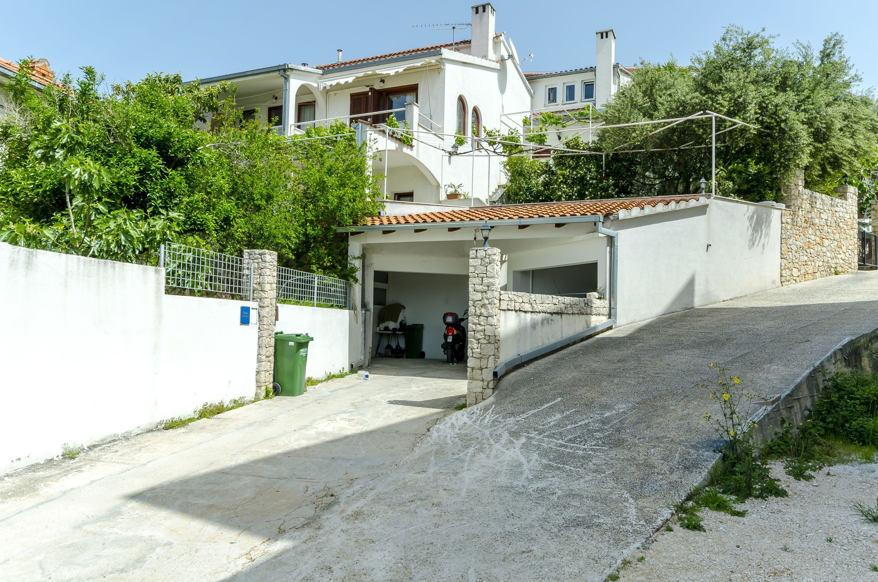 Un immobile residenziale con garage, un muro in pietra e strada privata asfaltata.