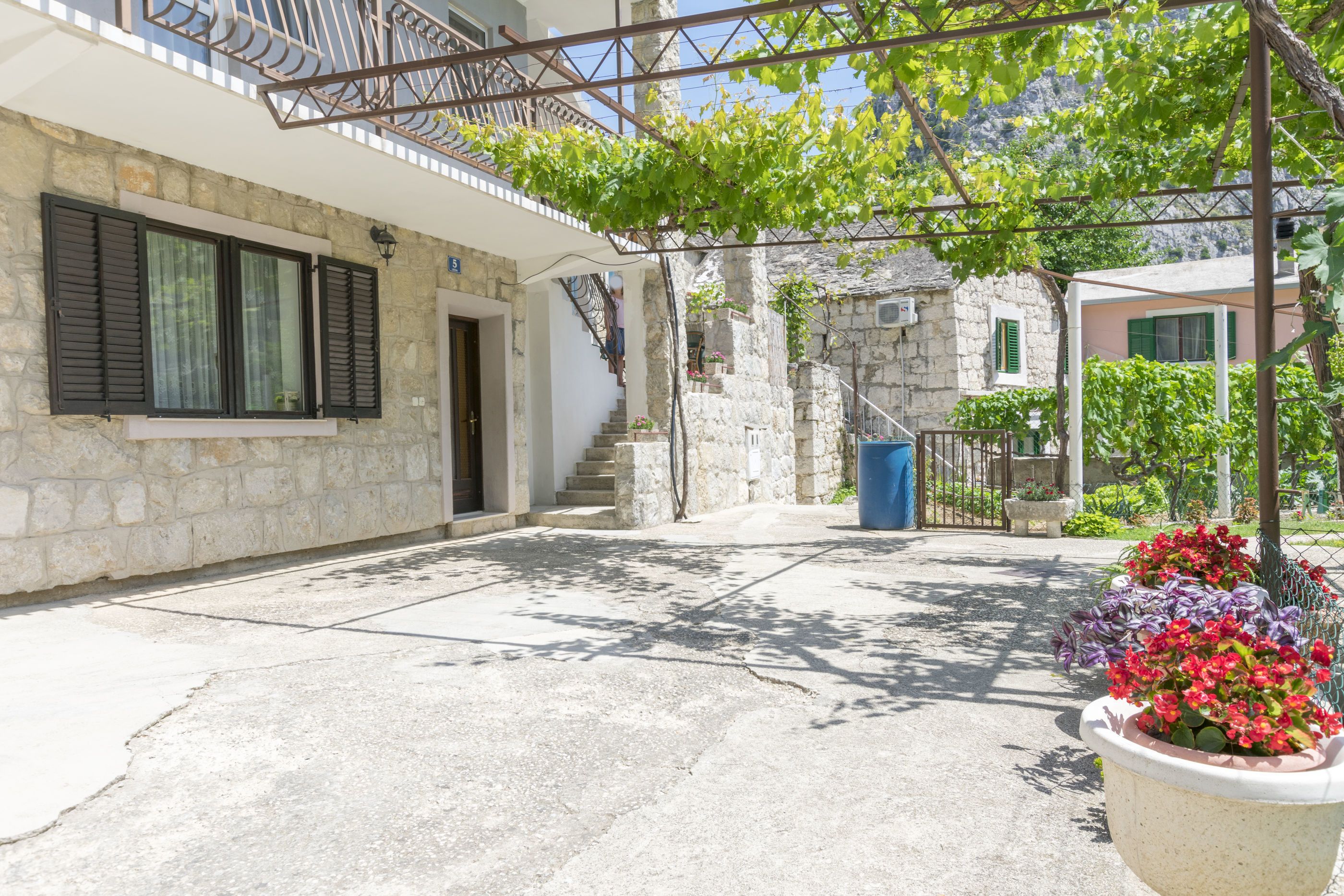 A courtyard with stone buildings, a staircase, and potted plants.
