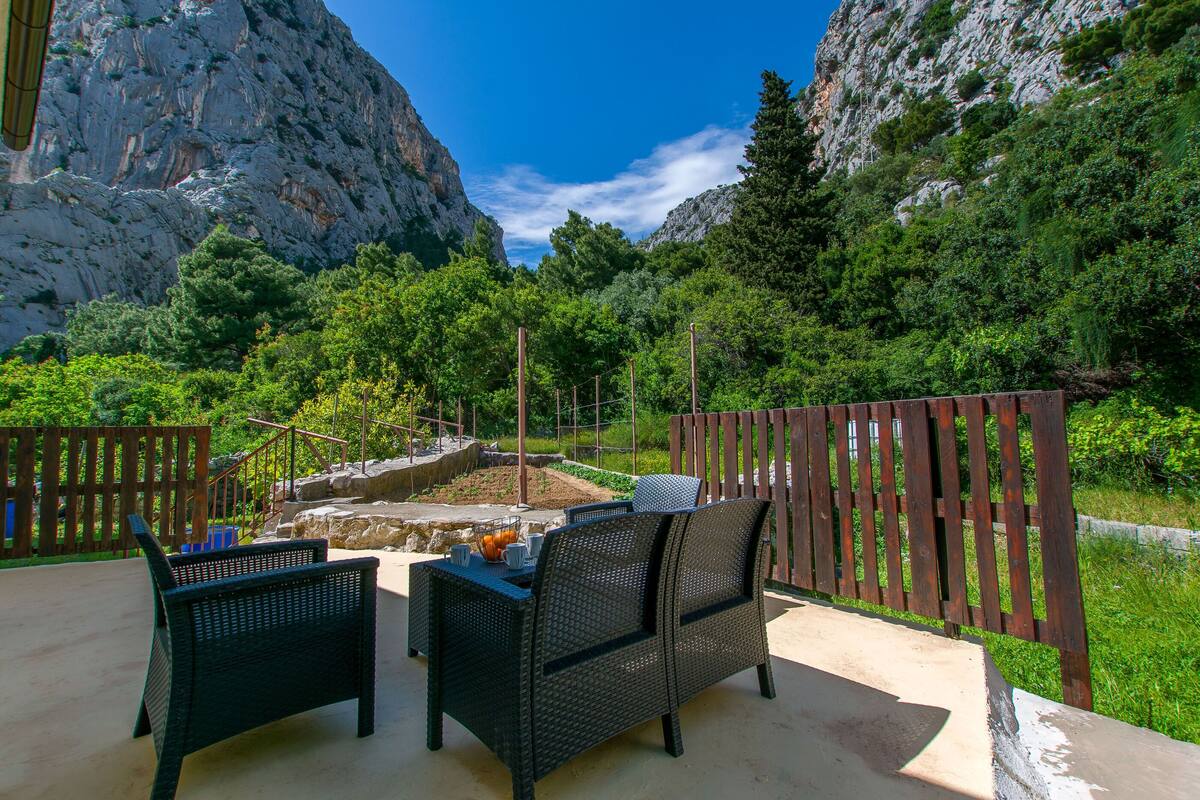 An outdoor seating area with wicker furniture and a view of rocky mountains.