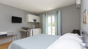 A bedroom with a bed, a desk, a chair, a microwave, and a TV. - Apartments Cozy Apartments (Vodice)