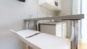 A clinical examination table in a room with a kitchenette, a flat-screen TV, and a stone-patterned backsplash. - Apartments Cozy Apartments (Vodice)