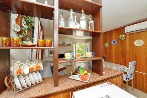 A kitchen with wooden shelves, a countertop with a fruit plate, and a chair. - Apartment Velimir (Vir)