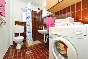 Une petite salle de bain comprenant des toilettes, un lavabo et un lave-linge.