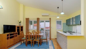 Ett kompakt bostadsutrymme med en matplats, ett kök och en TV.