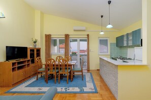 A compact living space with a dining area, a kitchen, and a TV. - Apartments Jasna (Novalja)