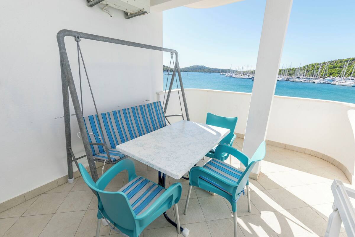 Ein Balkon mit Tisch und Stühlen, einer Schaukel und Blick auf Boote und Hügel.