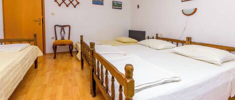 A hotel room with two single beds, a wooden floor, a wooden chair, and a door.