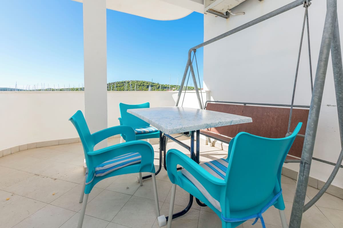 Ein Balkon mit Tisch und Stühlen, Blick aufs Meer und ein klarer Himmel.